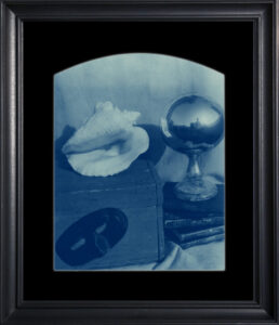 Framed still life with shell and mask.