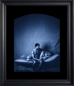 Framed art of two people on couch.