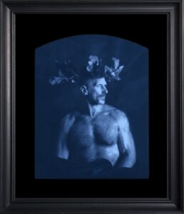 Shirtless man with crown, framed portrait.