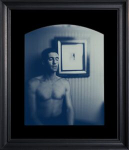 Shirtless man with eyes closed, framed photograph.