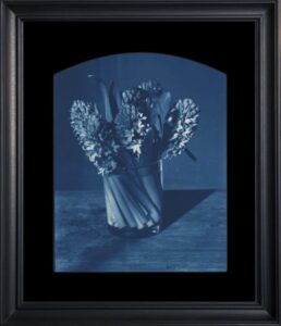 Framed blue-tinted flowers in a vase.