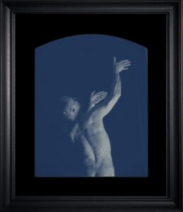 Man reaching upwards in artistic blue photograph.