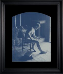 Man sitting on chair in dim light.