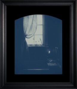 Framed window with curtain in dim light.