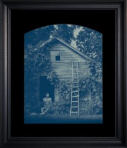 Man sitting by rustic building with ladder.