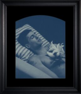 Man lying with lilies, monochrome photograph.