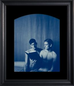 Two men reading a book together.