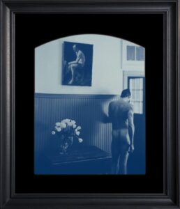 Nude figure in room with photograph.