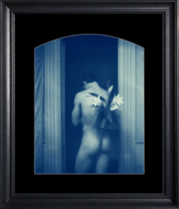 Nude figure holding flowers in doorway.